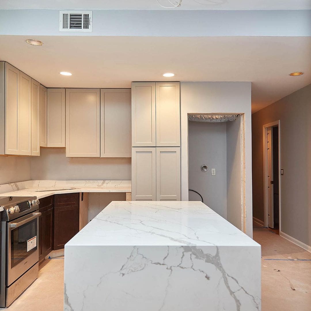 - 1 Polished marble kitchen island with beige cabinetry and modern appliances.