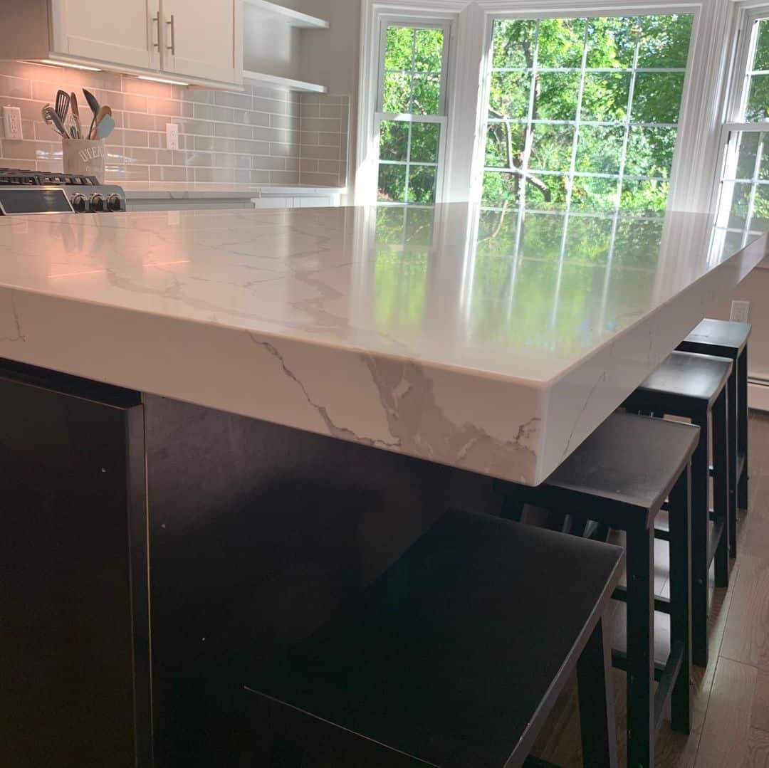 - 1 Elegant white marble kitchen island with black barstools and large windows, showcasing premium marbl.