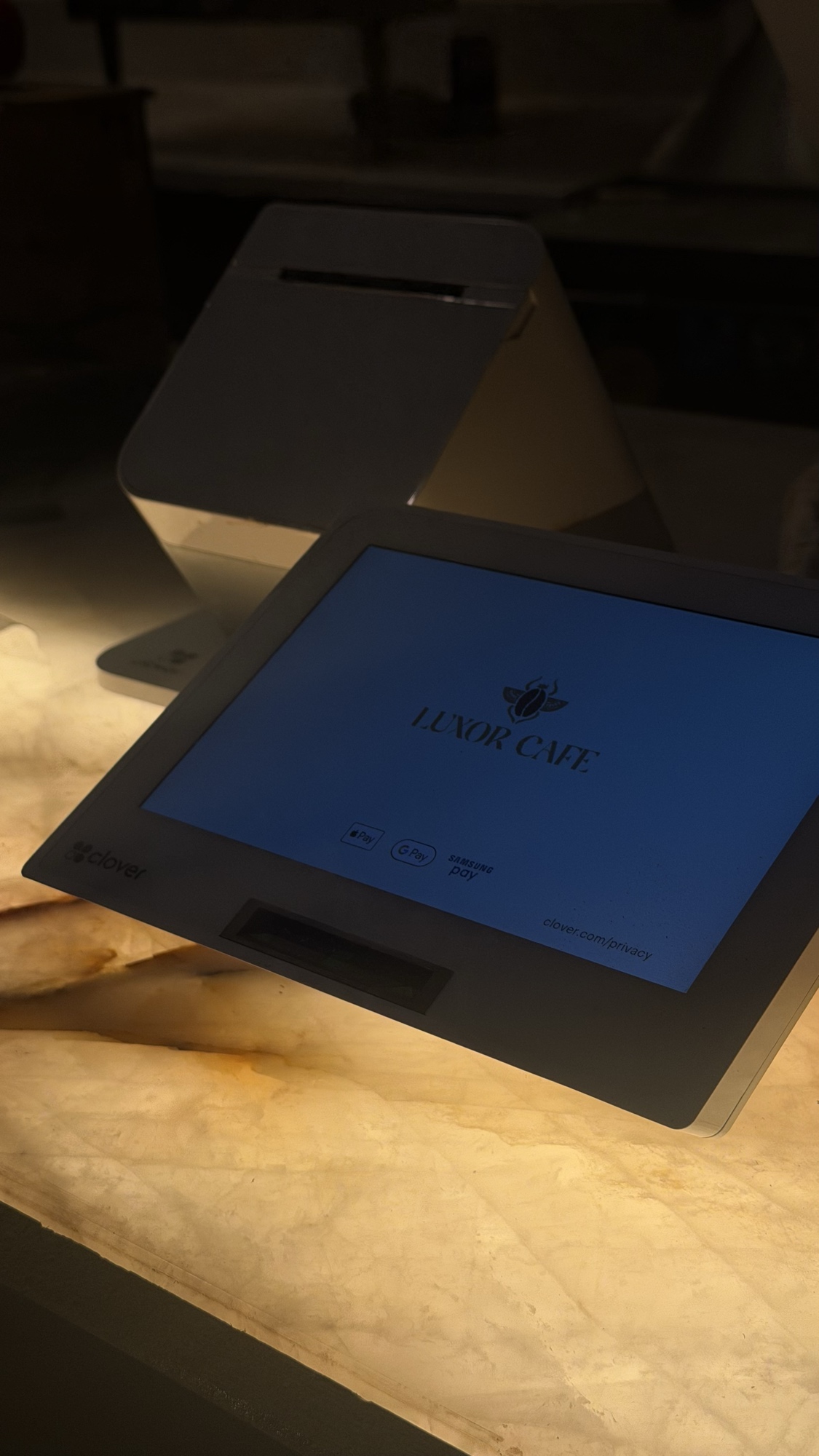 - 1 Backlit Patagonia quartzite counter glowing warm amber under a Clover POS terminal at Luxor Cafe
